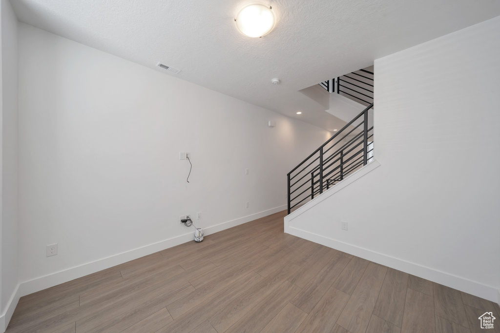 Unfurnished living room with stairs, baseboards, visible vents, and wood finished floors