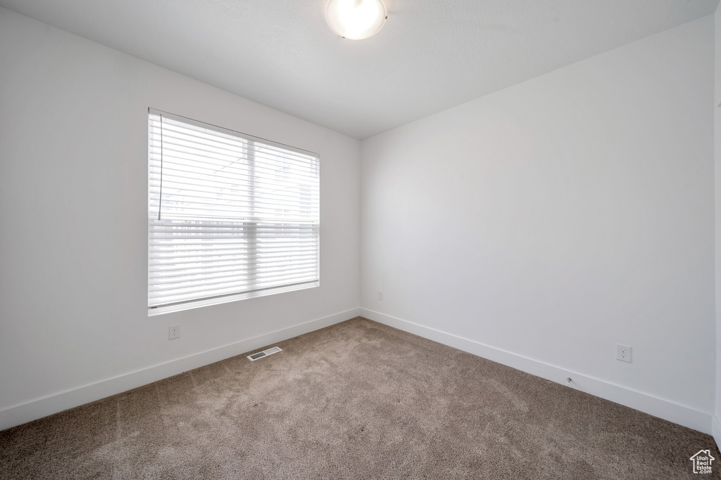 Carpeted spare room with baseboards and visible vents