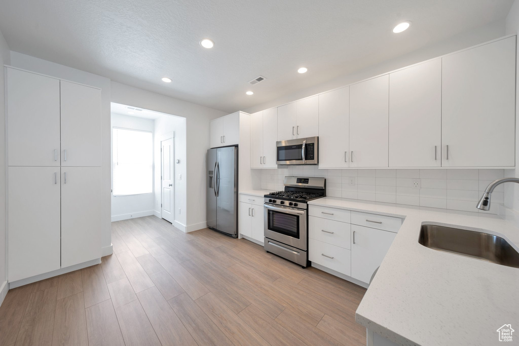 Kitchen featuring a sink, stainless steel appliances, light countertops, tasteful backsplash, and recessed lighting