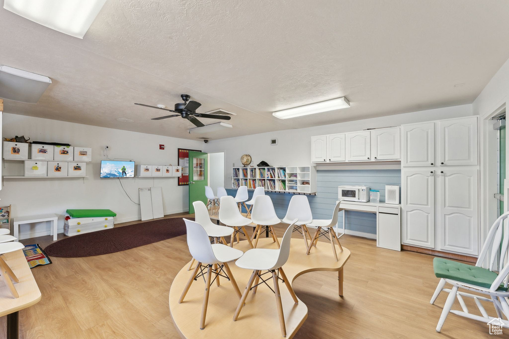 Dining area featuring light wood-style flooring, ceiling fan, and a textured ceiling