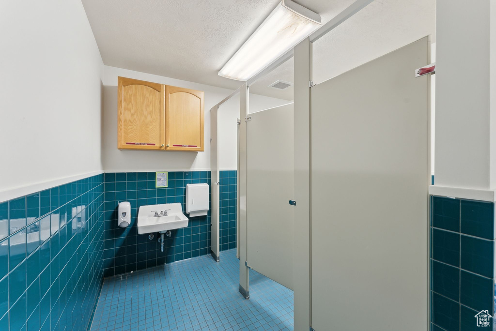 Bathroom featuring tile walls, visible vents, a sink, tile patterned floors, and a wainscoted wall