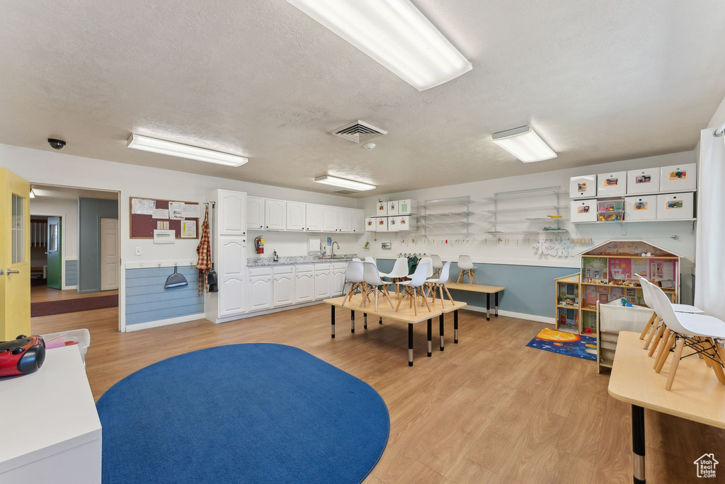 Playroom featuring baseboards, light wood-style flooring, visible vents, and a textured ceiling