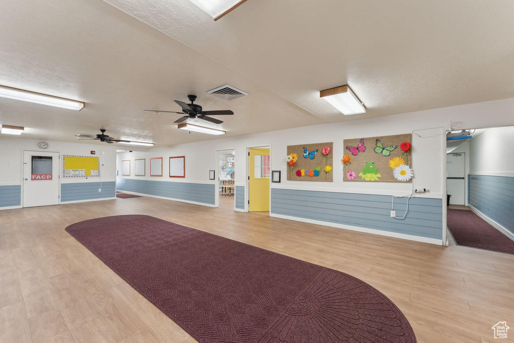 Miscellaneous room featuring a wainscoted wall, wood finished floors, visible vents, ceiling fan, and baseboards