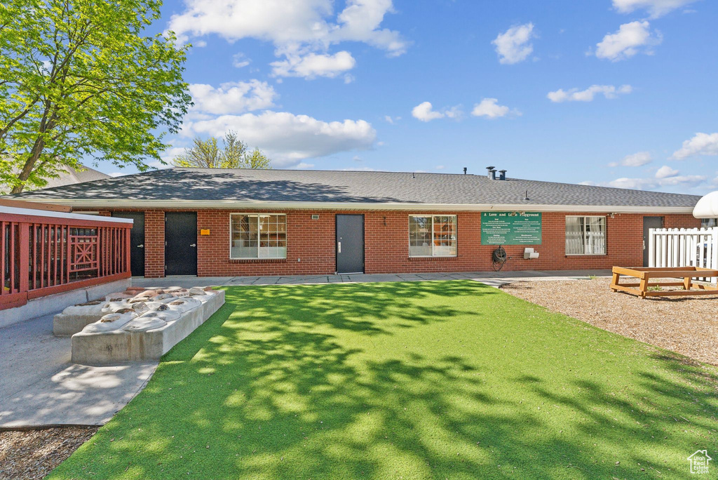 Rear view of property featuring a yard, brick siding, and roof with shingles