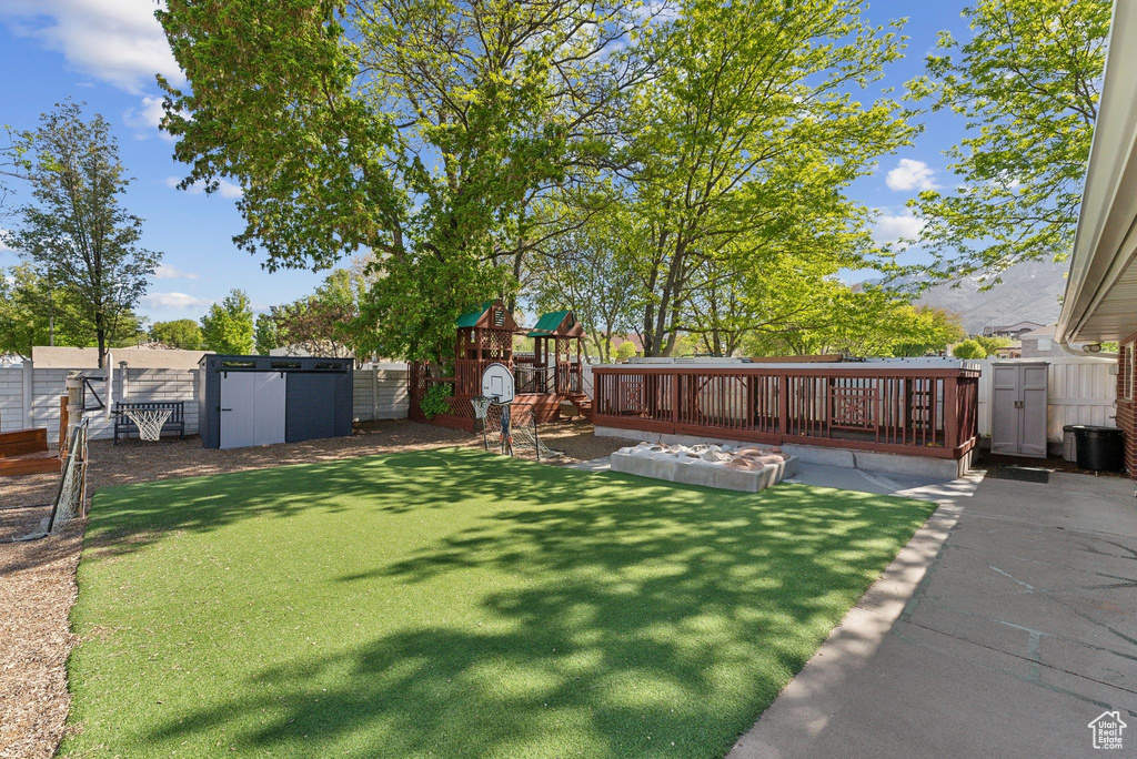 View of yard with a fenced backyard, an outdoor structure, a playground, and a shed