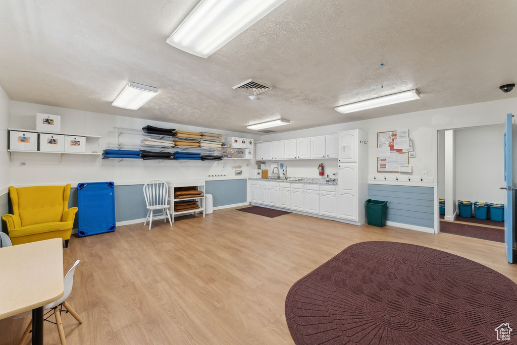 Miscellaneous room with baseboards, light wood finished floors, visible vents, and a textured ceiling