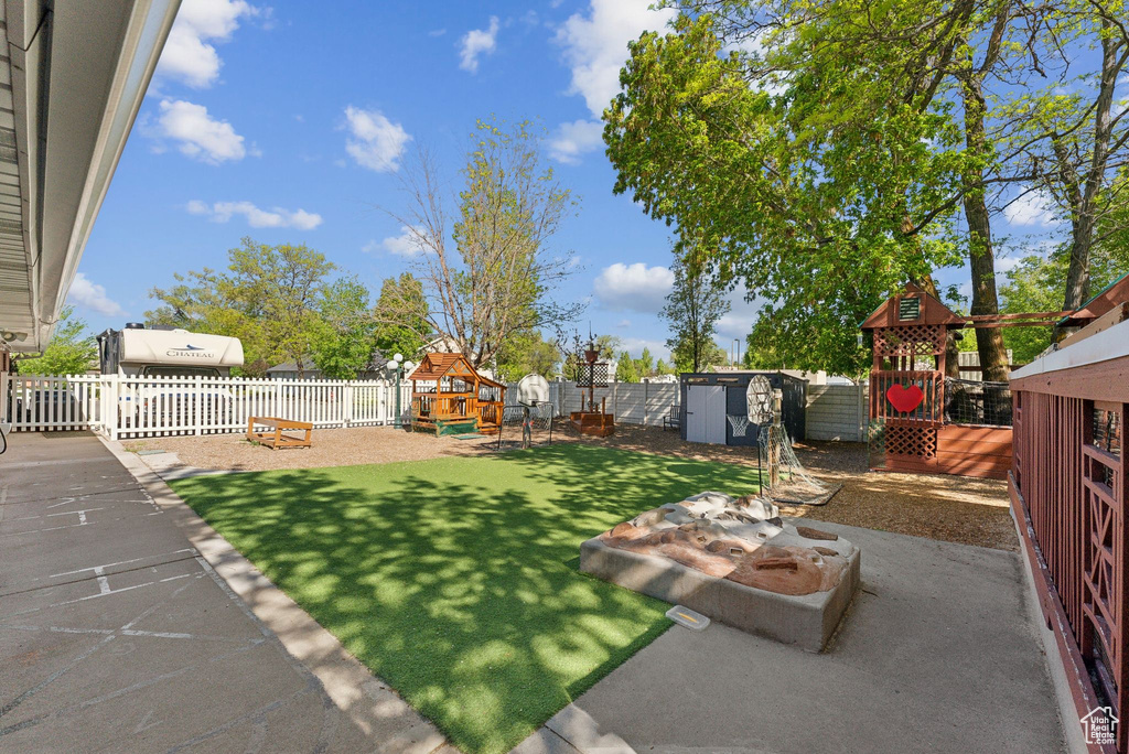 View of yard featuring a fenced backyard, a playground, and a storage unit