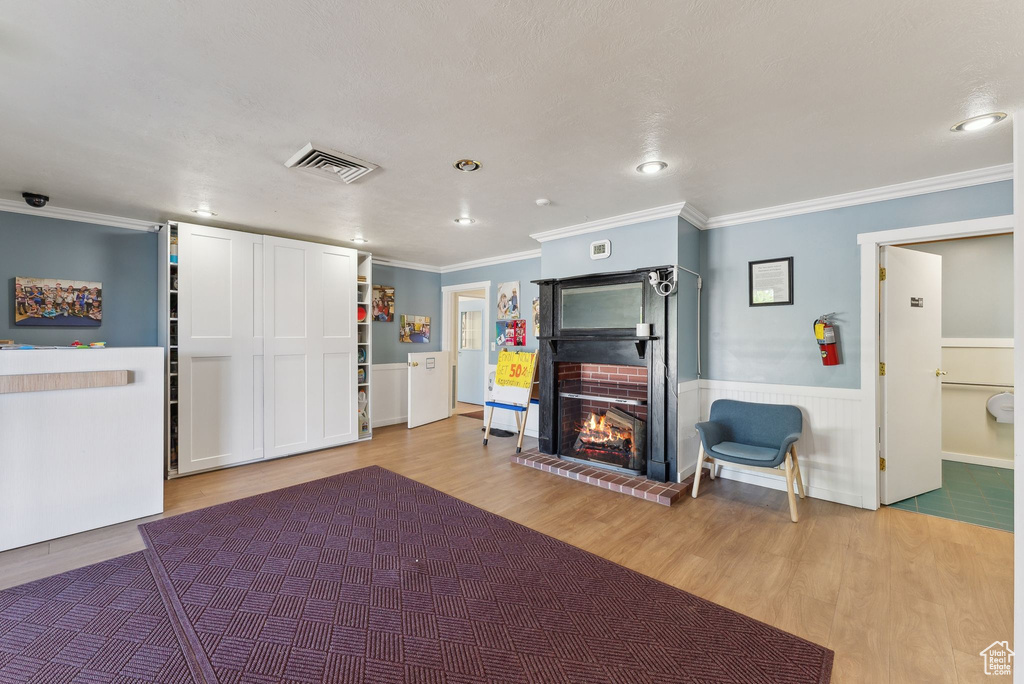 Interior space with recessed lighting, ornamental molding, visible vents, a brick fireplace, and wood finished floors