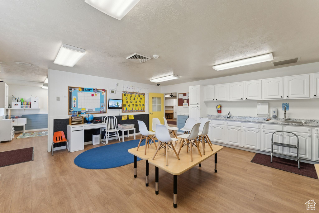 Dining area with light wood finished floors, visible vents, and a textured ceiling