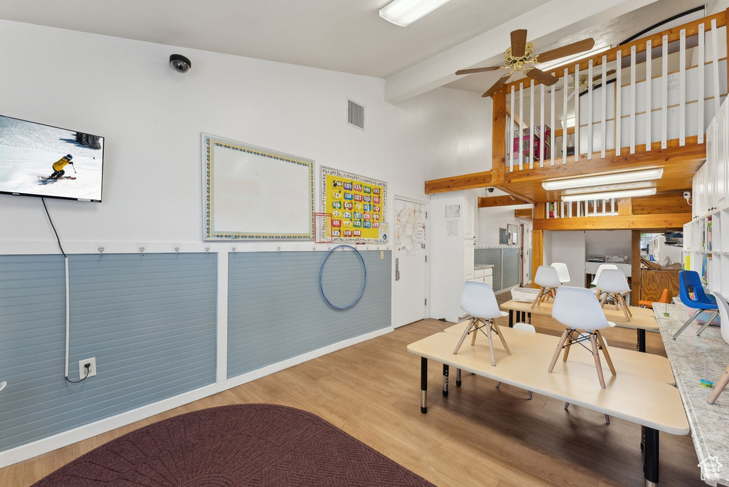 Living area with a ceiling fan, visible vents, vaulted ceiling with beams, and wood finished floors