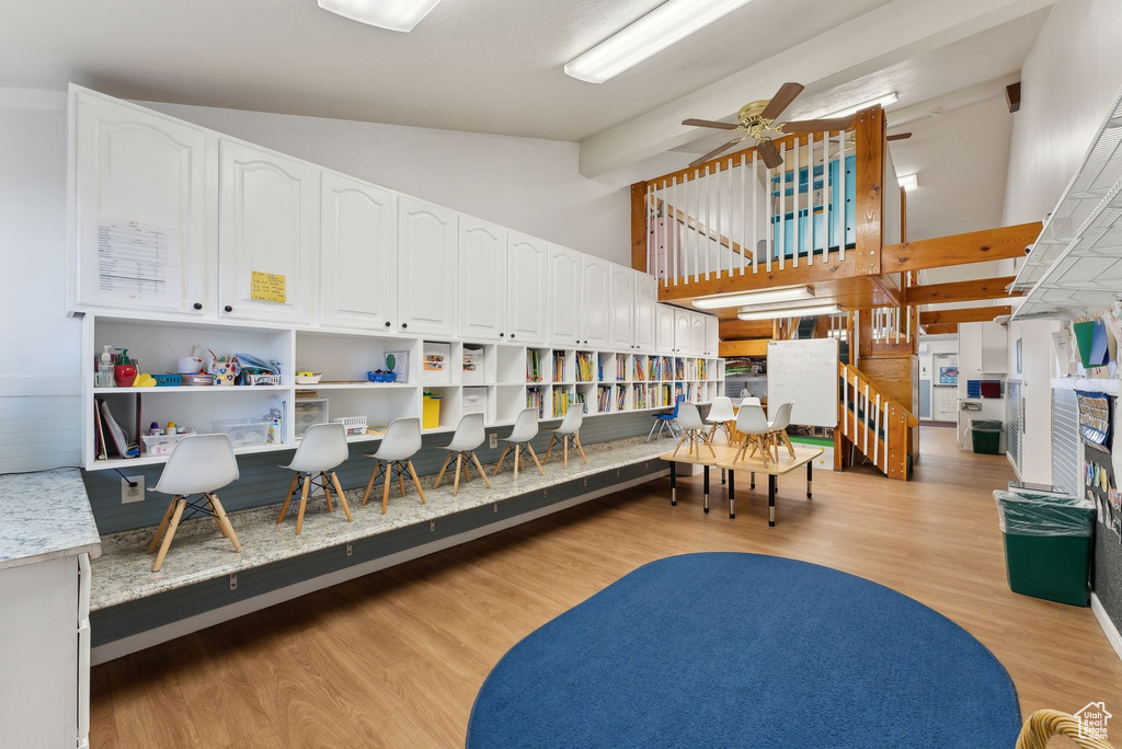 Interior space with light wood-type flooring, a ceiling fan, and high vaulted ceiling