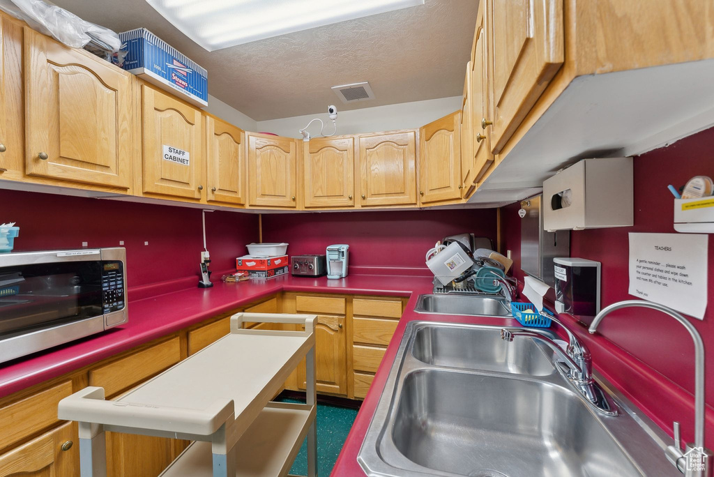 Kitchen featuring a sink, stainless steel microwave, a textured ceiling, and visible vents
