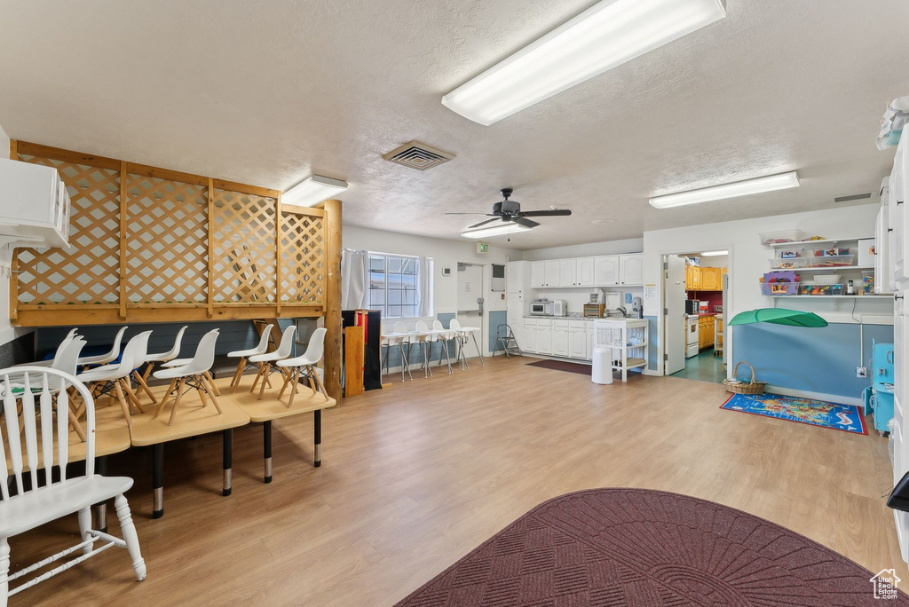 Interior space featuring ceiling fan, light wood-style flooring, visible vents, and a textured ceiling