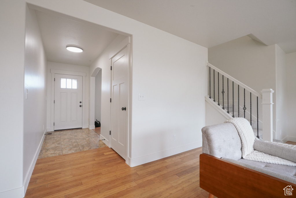 Entryway featuring arched walkways, baseboards, light wood finished floors, and stairway