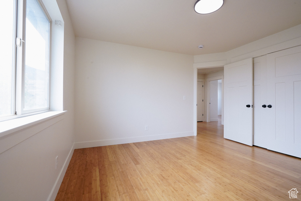 Unfurnished bedroom with light wood-style flooring, baseboards, and a closet