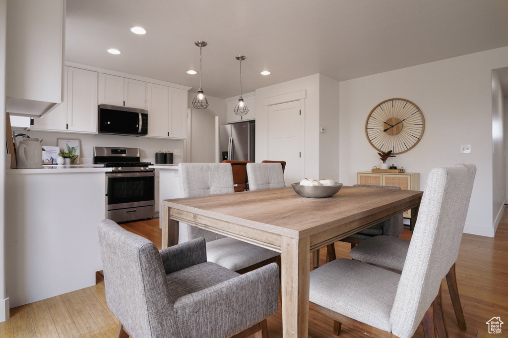 Dining room with light wood finished floors and recessed lighting