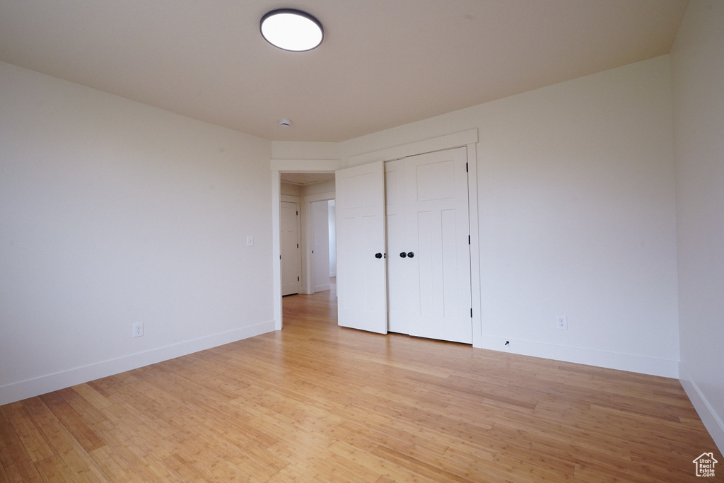 Unfurnished bedroom featuring baseboards, a closet, and light wood-type flooring