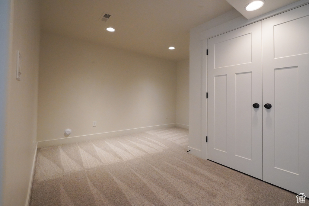 Unfurnished bedroom featuring light colored carpet, a closet, baseboards, and recessed lighting