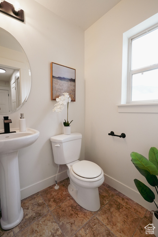 Half bath featuring a sink, toilet, and baseboards