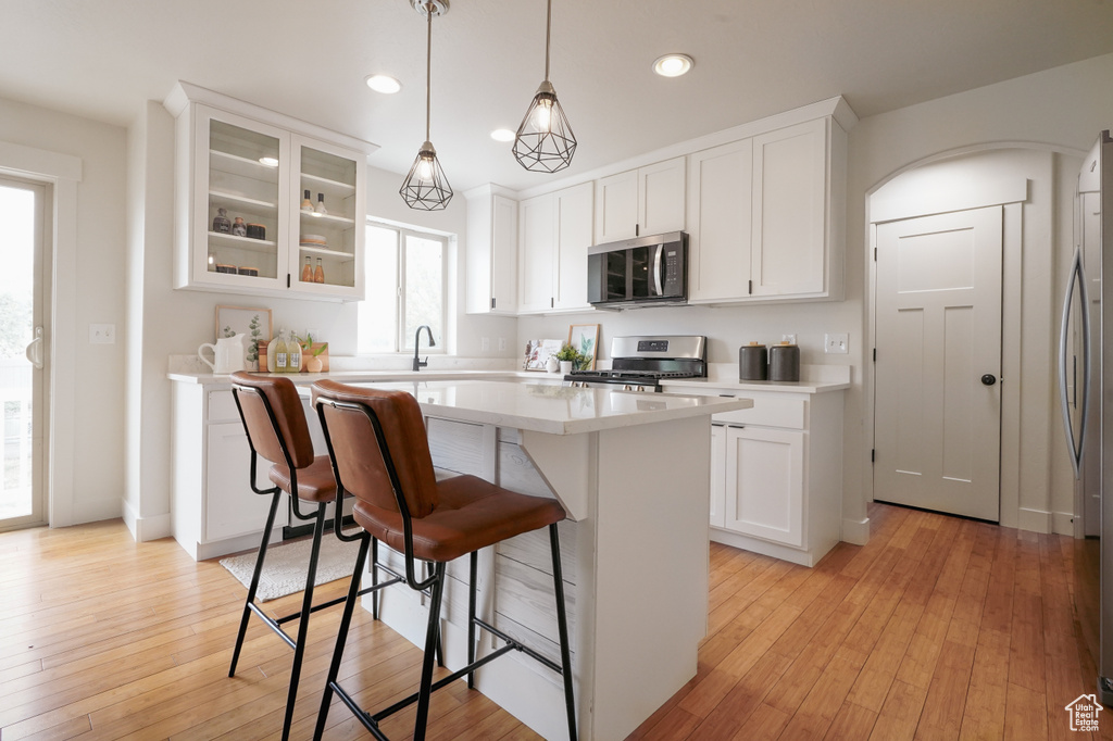 Kitchen featuring a breakfast bar, stainless steel appliances, a kitchen island, and white cabinets