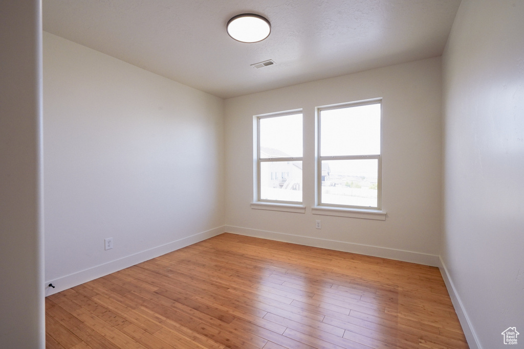 Spare room featuring light wood-style floors, visible vents, and baseboards