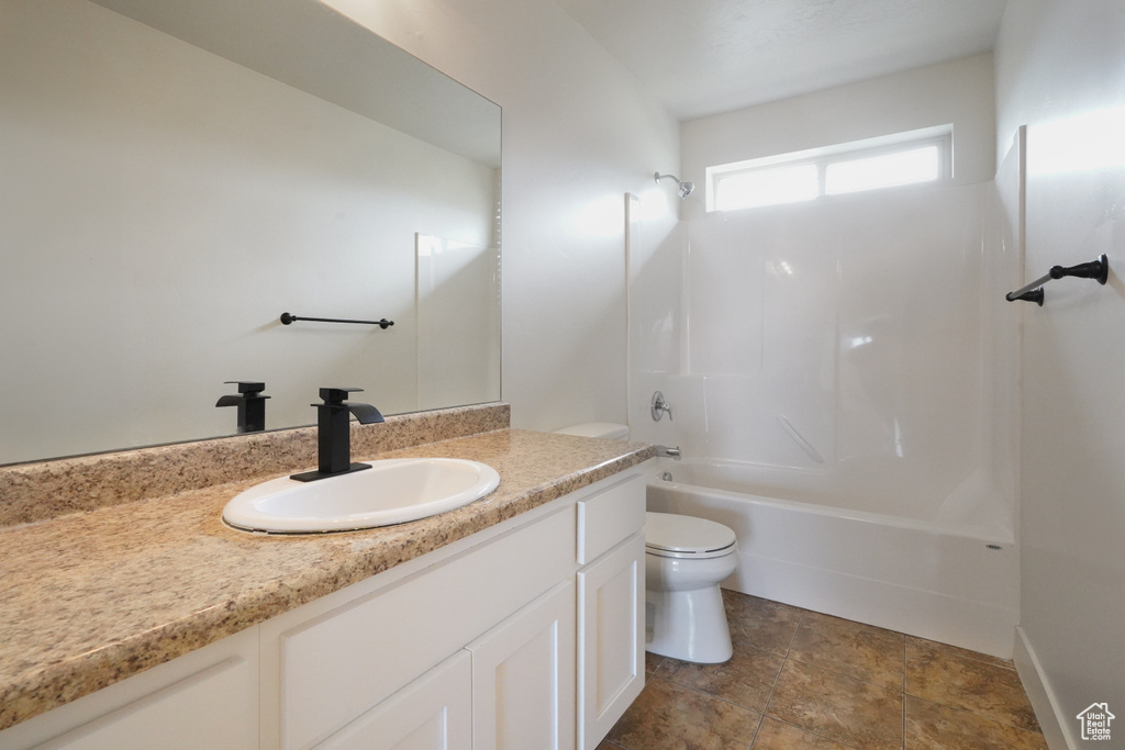 Bathroom featuring toilet, tub / shower combination, vanity, and stone finish flooring