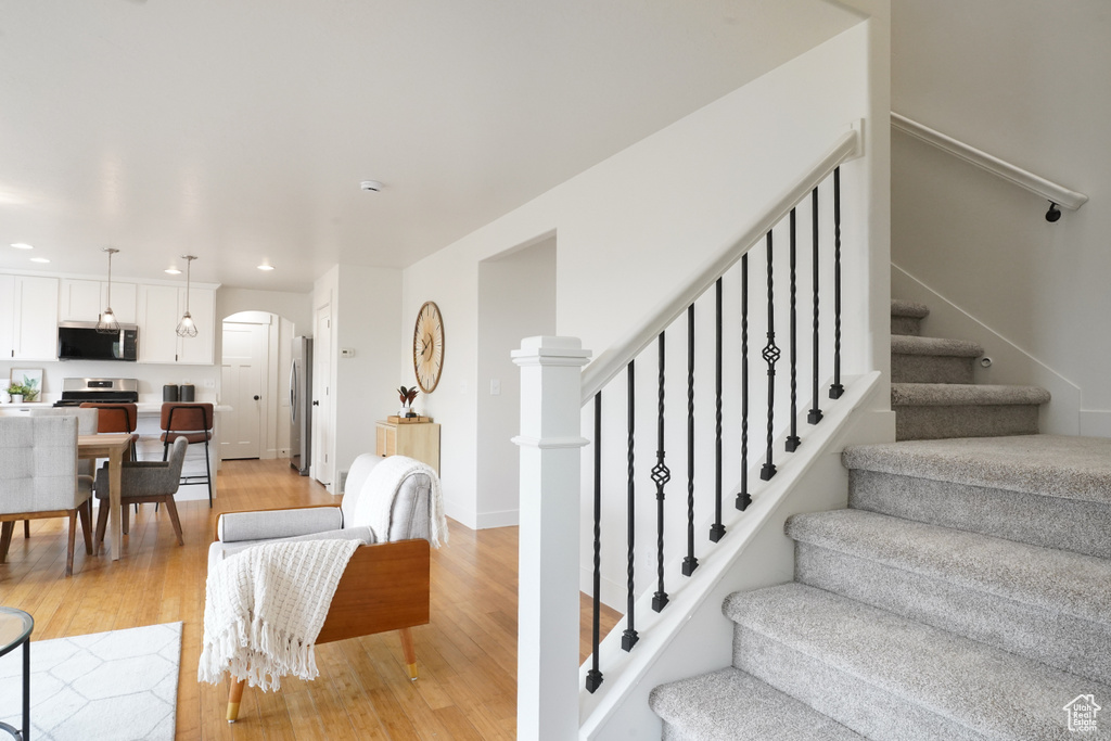 Staircase with arched walkways, recessed lighting, and wood finished floors