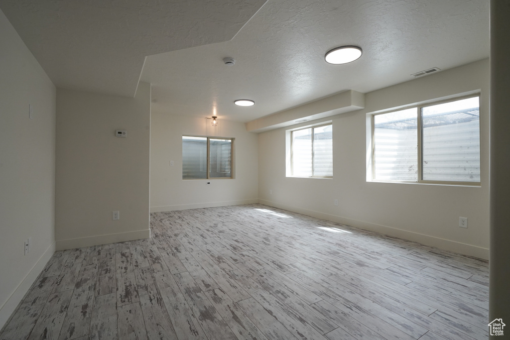 Unfurnished room featuring visible vents, wood finished floors, and baseboards