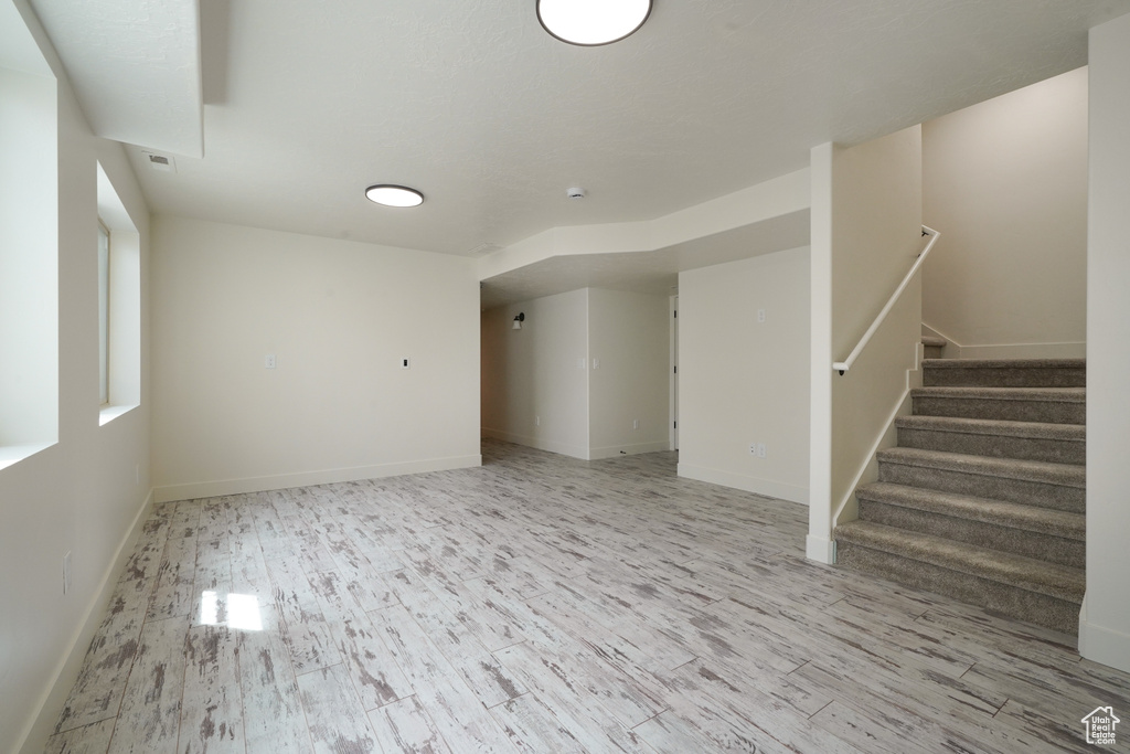Unfurnished living room with baseboards, stairway, and wood finished floors