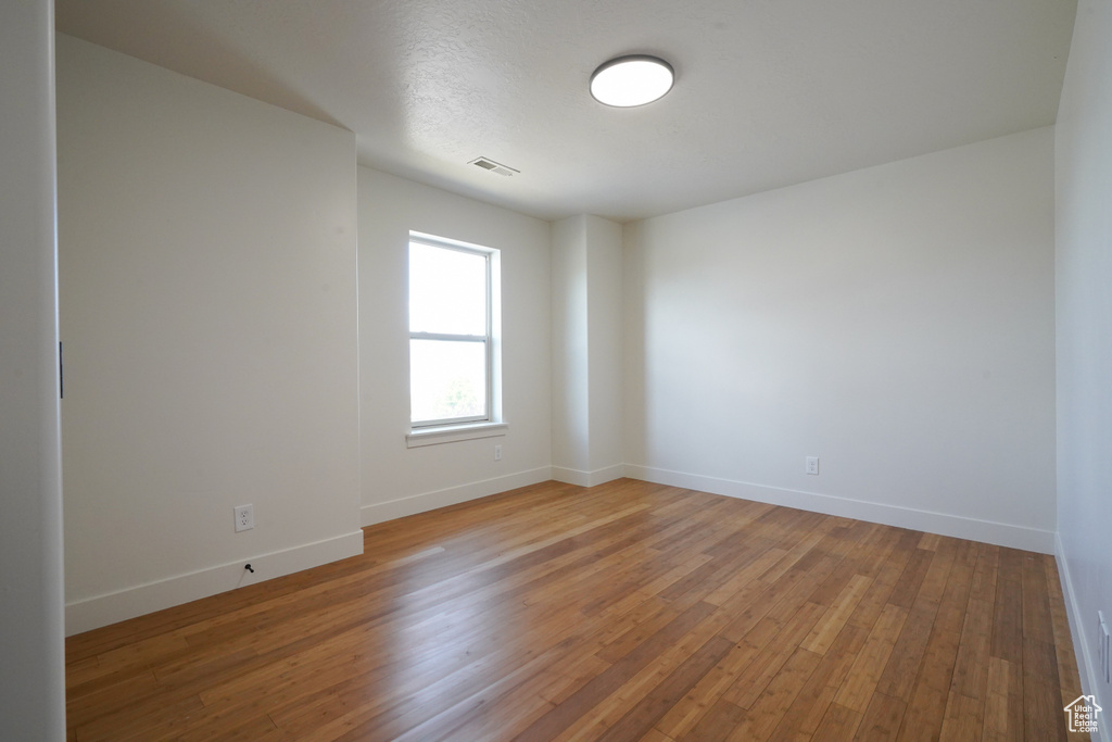 Unfurnished room featuring wood finished floors, visible vents, and baseboards