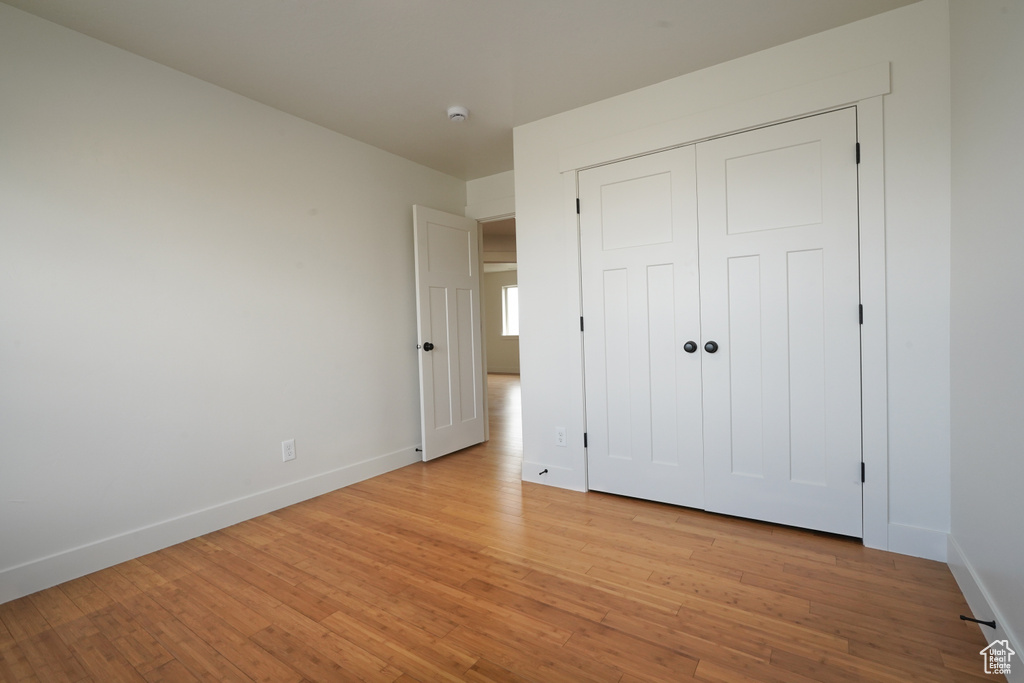 Unfurnished bedroom with light wood-style flooring, baseboards, and a closet