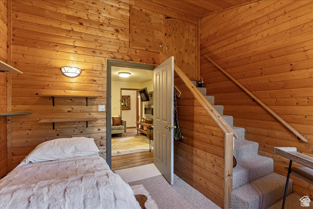 Carpeted bedroom with wooden ceiling and wooden walls