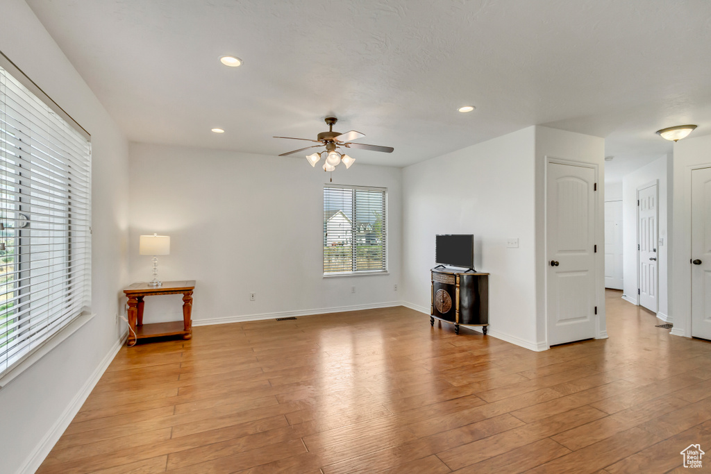 Unfurnished living room with light wood-type flooring, baseboards, a ceiling fan, and recessed lighting