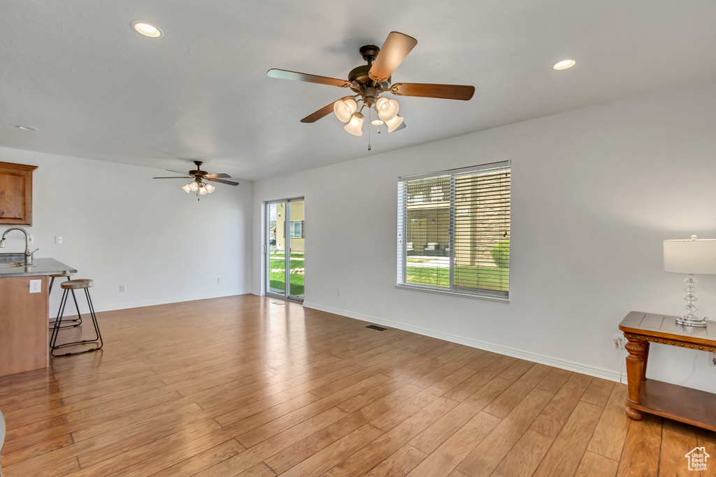 Unfurnished living room with light wood-type flooring, baseboards, a ceiling fan, and recessed lighting