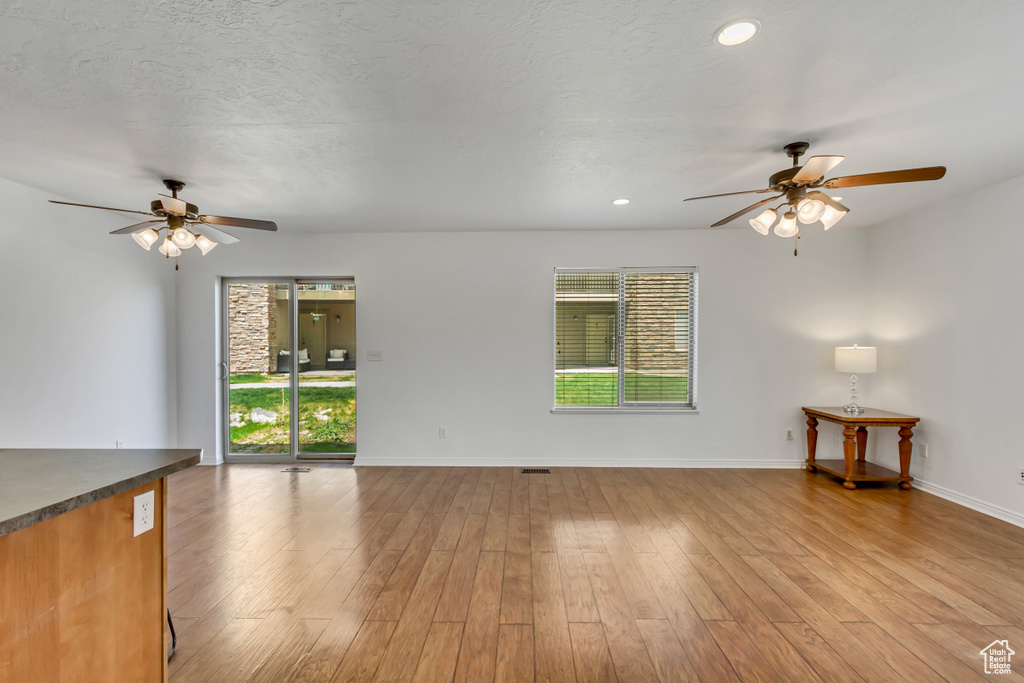 Unfurnished living room with baseboards, a ceiling fan, and plenty of natural light
