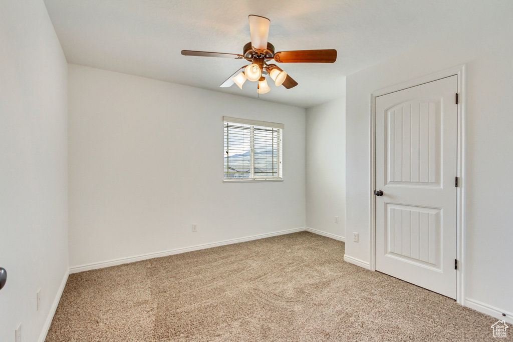 Unfurnished room with light colored carpet, baseboards, and a ceiling fan