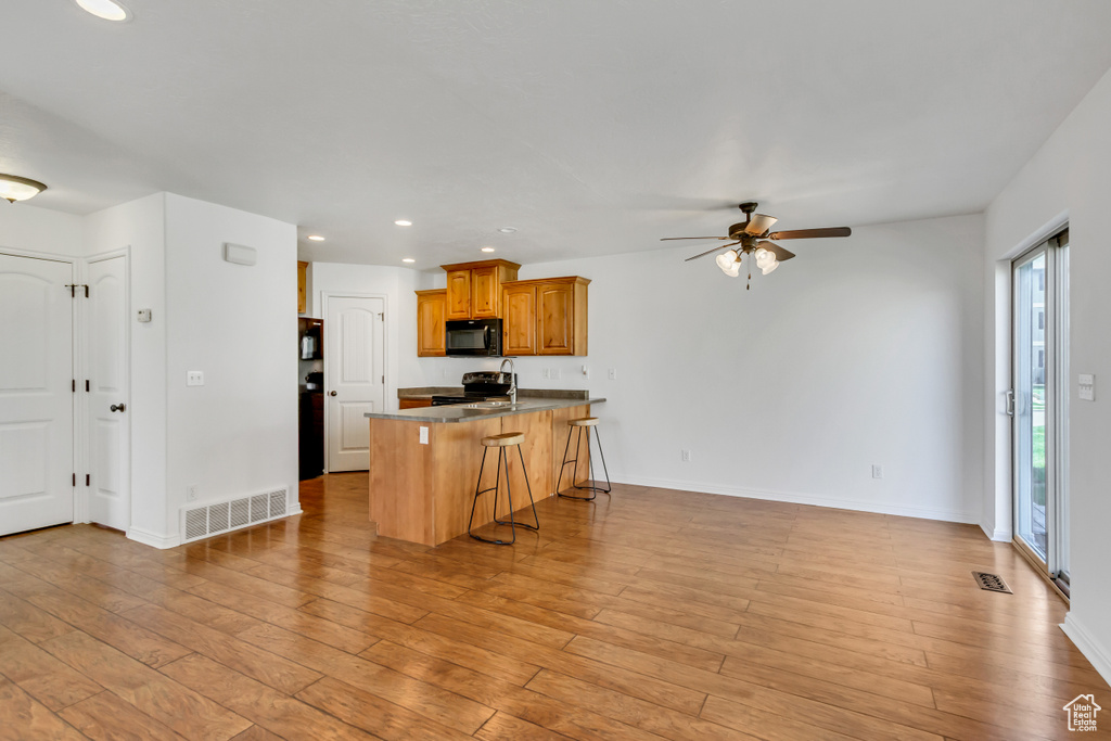 Kitchen featuring recessed lighting, a healthy amount of sunlight, a breakfast bar, and black microwave