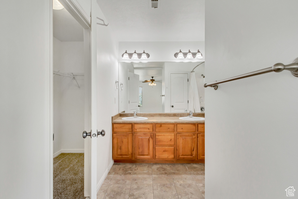 Full bathroom with double vanity, a spacious closet, ceiling fan, and a sink