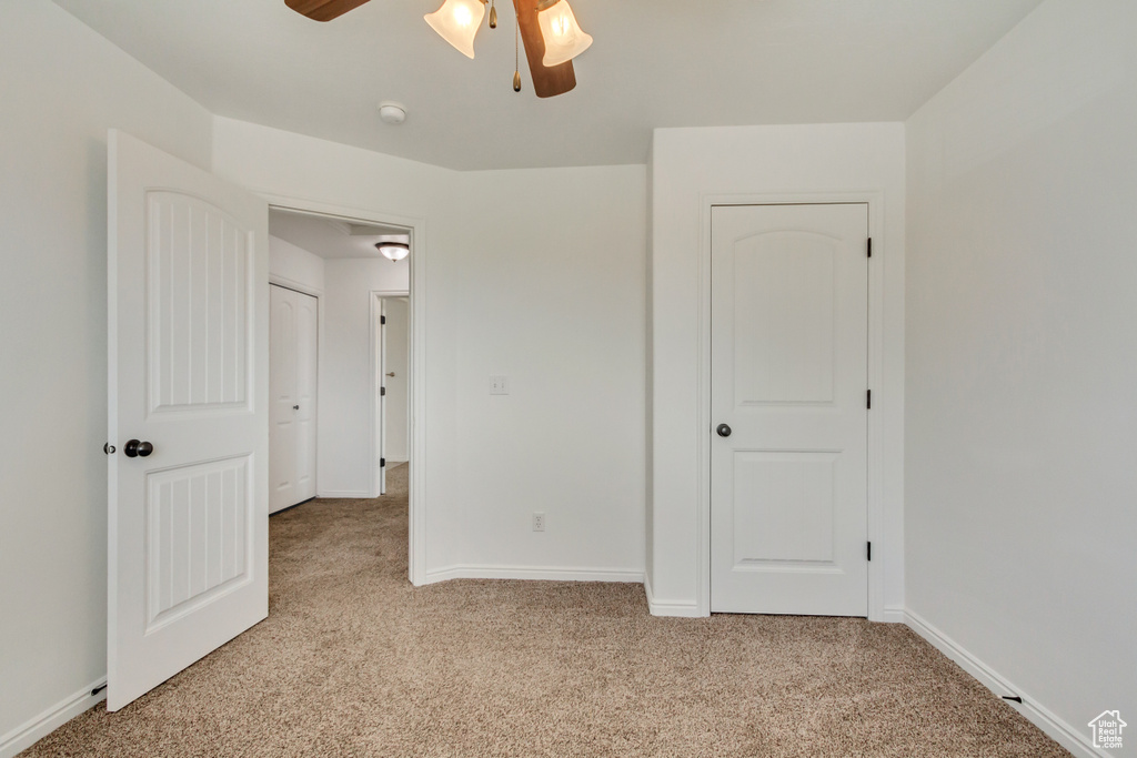 Unfurnished bedroom featuring light colored carpet, baseboards, and ceiling fan