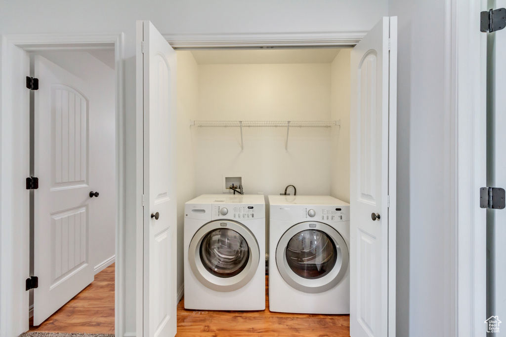 Washroom featuring washing machine and clothes dryer, laundry area, and light wood-type flooring