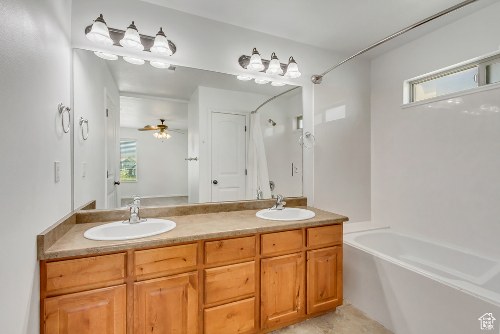 Bathroom featuring a bath, ceiling fan, double vanity, and a sink