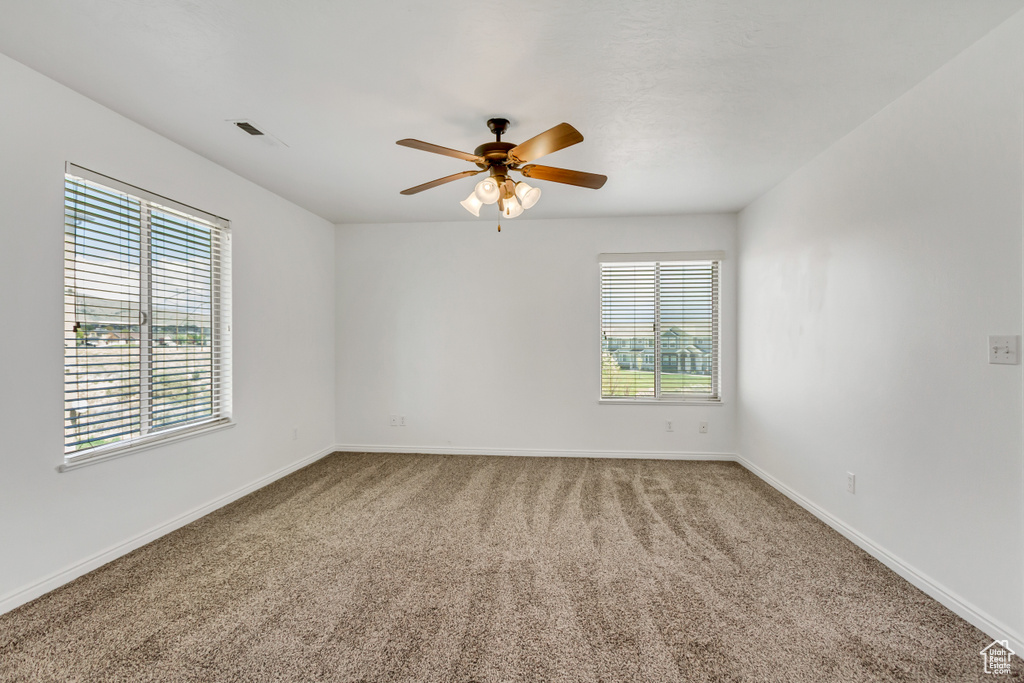 Spare room featuring a ceiling fan, carpet flooring, visible vents, and baseboards