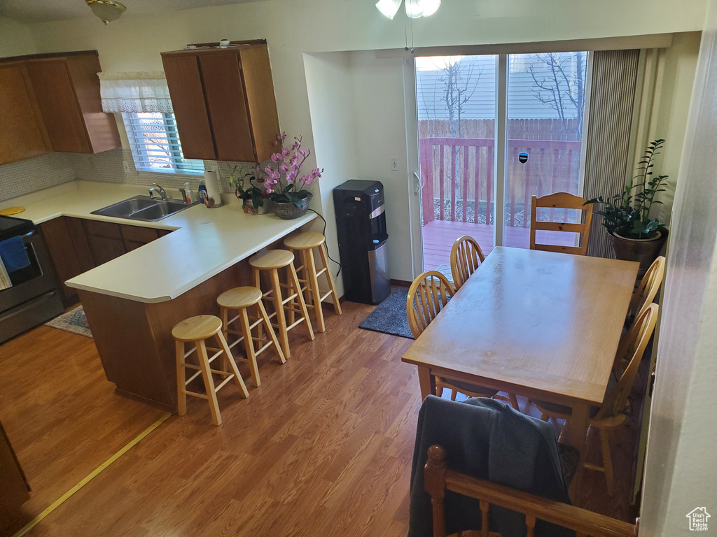 Kitchen with a breakfast bar area, stainless steel range with electric stovetop, light wood-style flooring, a sink, and light countertops