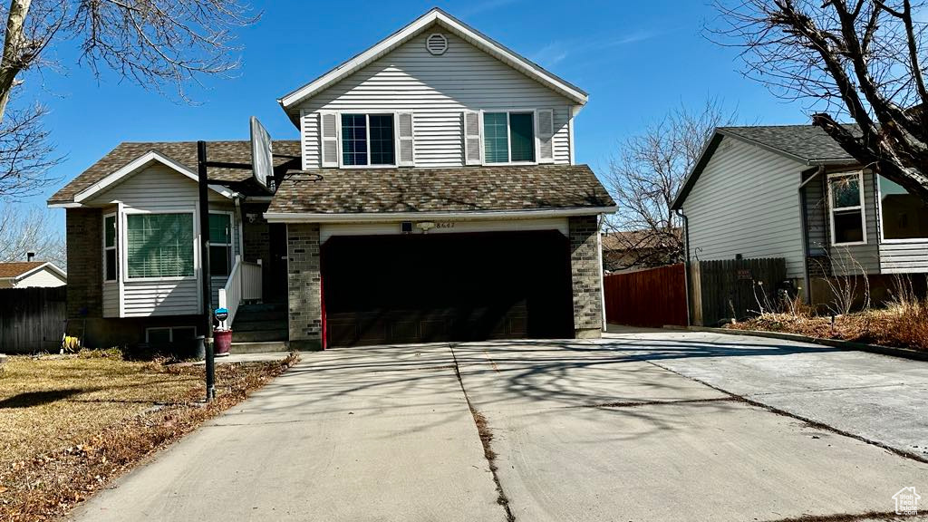 Tri-level home with fence, an attached garage, and driveway