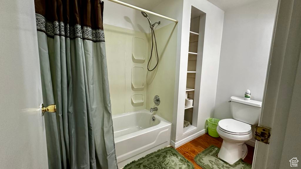 Full bath featuring toilet, shower / tub combo, and wood finished floors