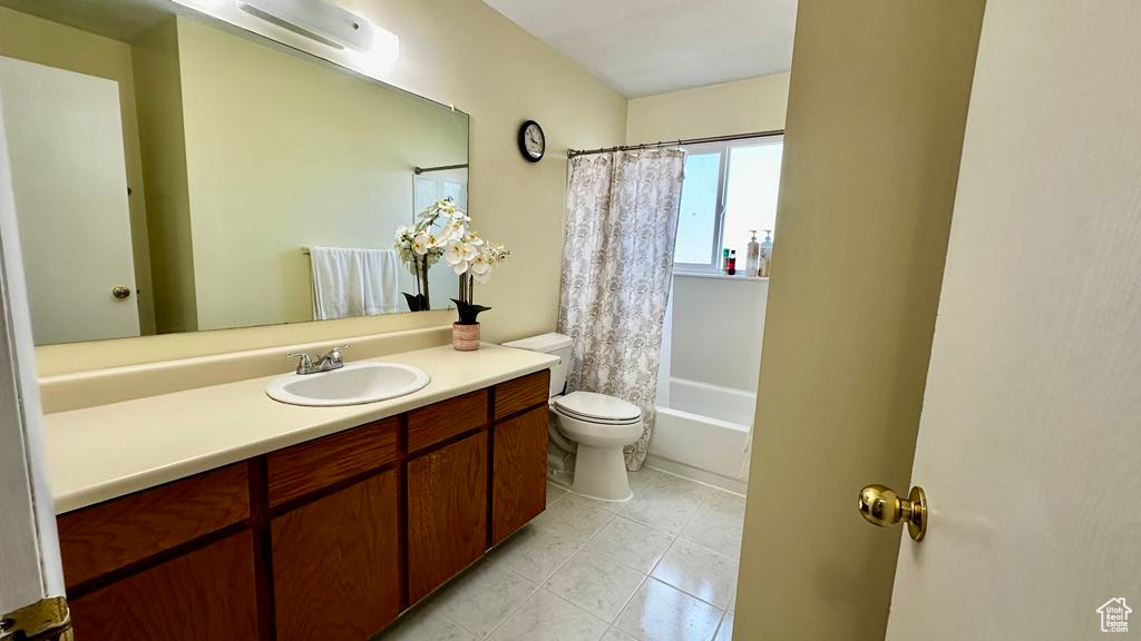 Full bathroom featuring toilet, shower / tub combo with curtain, tile patterned floors, and vanity