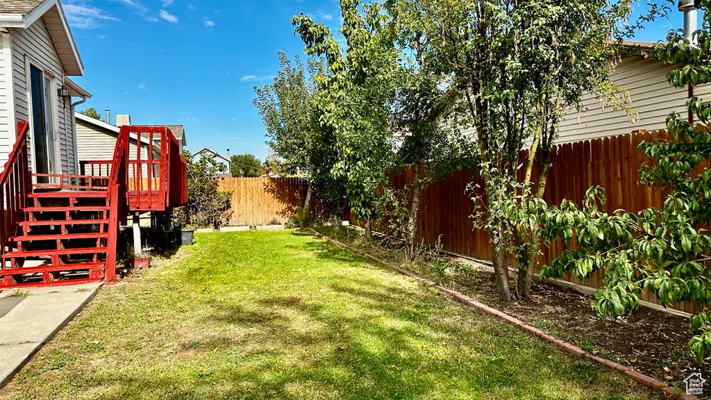 View of yard with a fenced backyard, a deck, and stairs