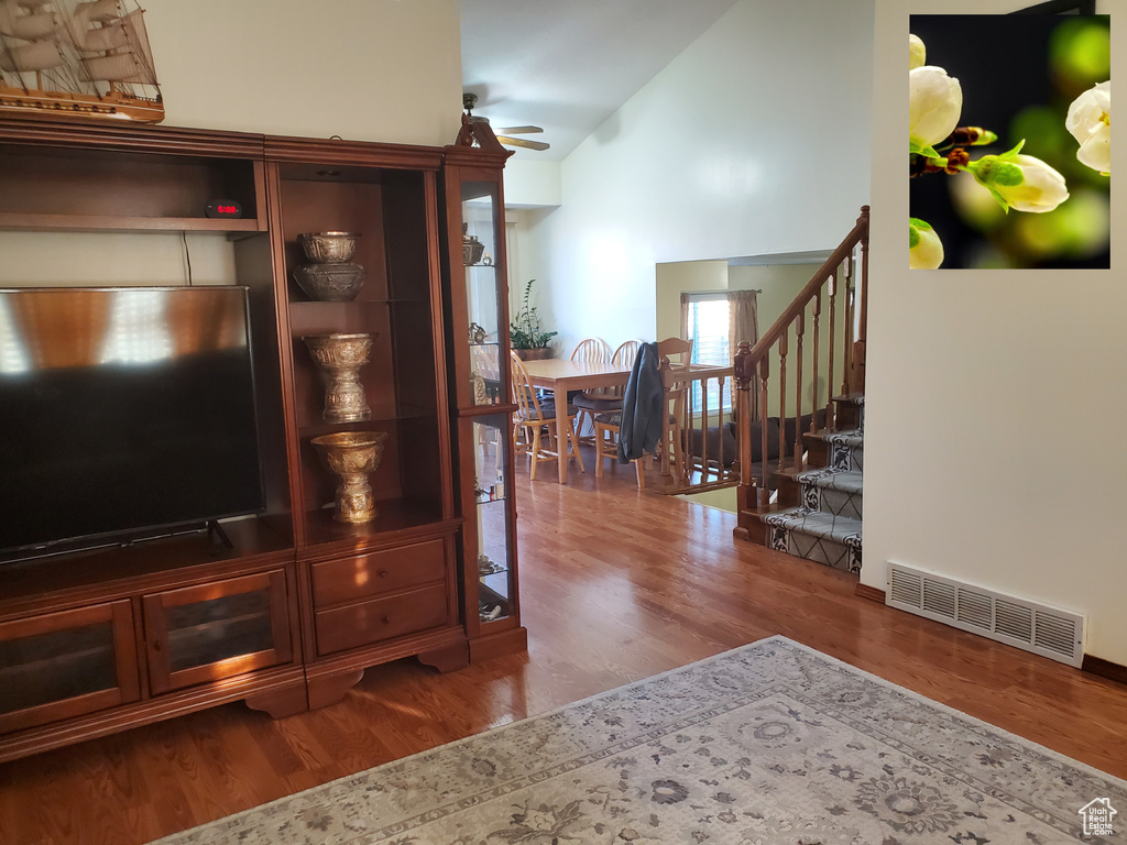 Living room with visible vents, wood finished floors, lofted ceiling, and stairs