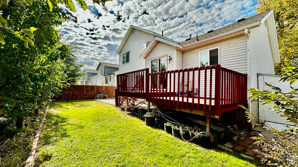 Back of house featuring a deck, fence, and a lawn