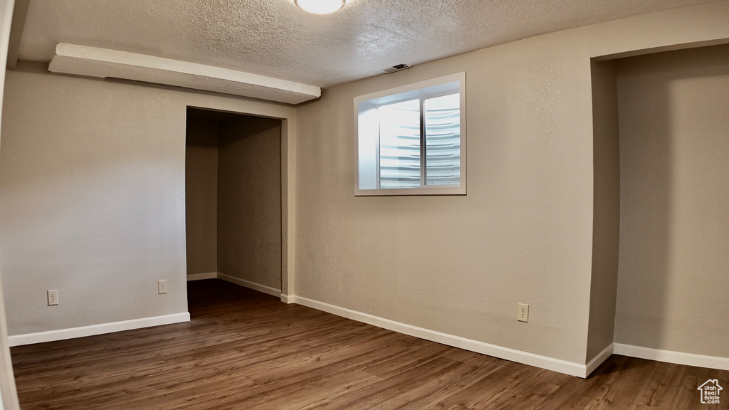 Spare room with baseboards, visible vents, a textured ceiling, and wood finished floors